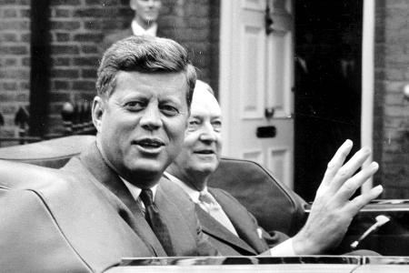 President John F Kennedy waves in an open car leaving Buckin...