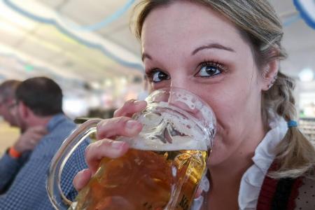 Eine Frau auf dem Oktoberfest trinkt eine Maß Bier
