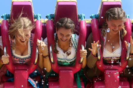 3 Mädchen im Dirndl fahren mit einem Karussell