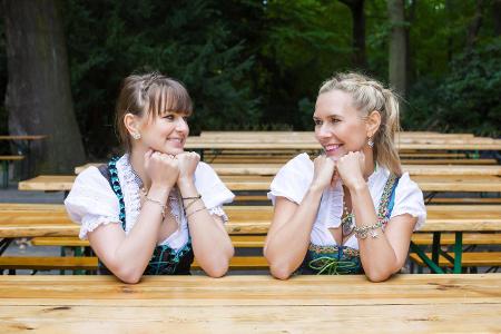 Zwei Frauen im Dirndl sitzen im leeren Biergarten