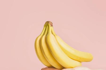 Eine Hand hält ein Bund Bananen