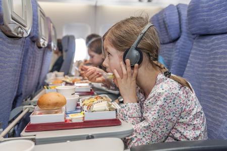 Girl watching movie on airplane while eating airline meal PU...