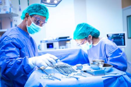 Ein Mann und eine Frau in OP-Kitteln sortieren OP-Instrumente.