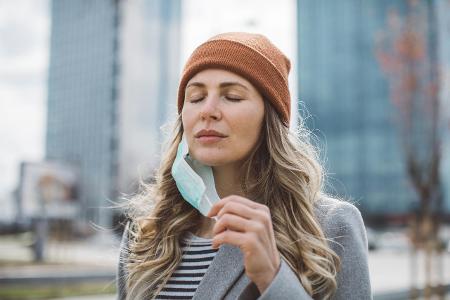 Frau zieht sich Maske ab und atmet durch