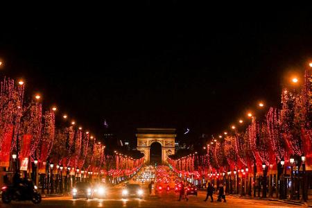 Ähnliches Bild, andere Stadt: Die Prachtstraße Avenue des Champs-Élysées führt mit rot erleuchteten Bäumen direkt auf den Ar...