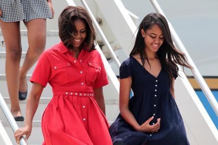 An der Seite von Tochter Malia bezaubert sie auf einer Venedigreise in einem roten Hemdblusenkleid von Michael Kors.