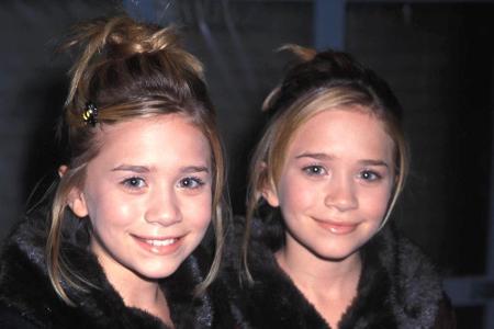 Bei einer Weihnachtsparty zeigen sich die hübschen Zwillinge 1998 mit stylischem Fellkragen und identischen Hochsteckfrisuren.