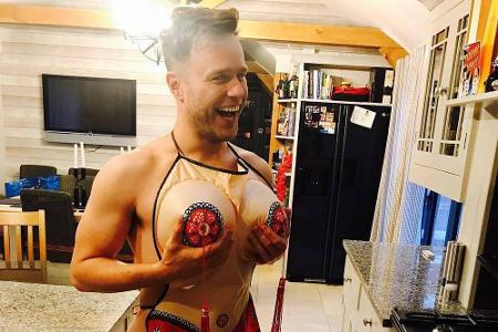 Mit nichts anderem als einer Schürze bekleidet, posierte Olly Murs in seiner Küche. Mit den Händen an dem aufblasbaren Vorba...