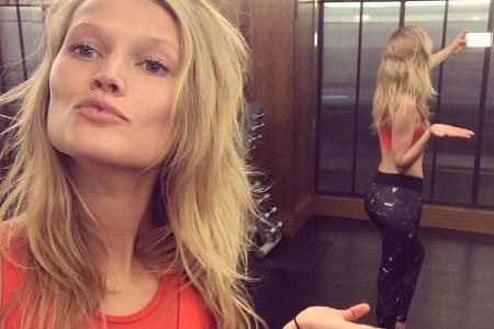 Toni Garrn steht mit dem Rücken vor einem Spiegel. Ihre Hand versucht sie dabei so zu positionieren, dass es aussieht, als w...