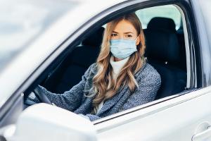 Eine junge Frau mit Schutzmaske im Auto