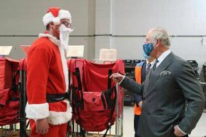 Prinz Charles spricht bei einem Besuch einer britischen Postfiliale mit einem als Weihnachtsmann verkleideten Mitarbeiter.