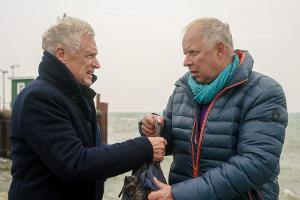 "Nord Nord Mord: Clüver und der tote Koch": Theo Clüver (Robert Atzorn) übergibt Josef Wenzel (Axel Milberg) am Hafen eine T...