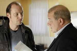 "Wilsberg: Gefahr in Verzug": Torsten Schmitt (Martin Brambach, l.) wird von Georg Wilsberg (Leonard Lansink) beim Durchsuch...