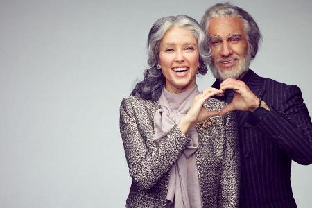 Rebecca Mir und Massimo Sinató blicken mit einem Lächeln in ihr älteres Spiegelbild