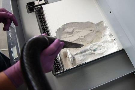 Nach dem 3D-Druck wird die fertige Figur aus dem Pulver befreit.