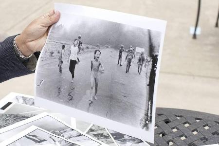 Fotograf Nick Út hält seine Aufnahme 