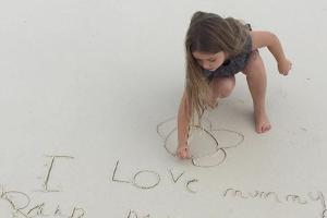 Harper Beckham schreibt eine Liebesbekundung in den Sand