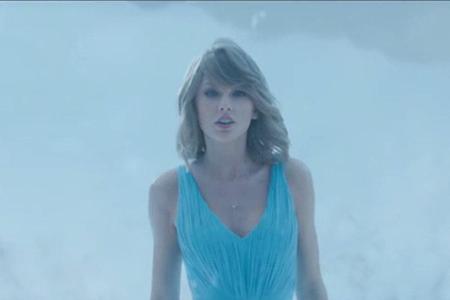 Im blauen Kleid schreitet Taylor Swift durch eine Schneelandschaft