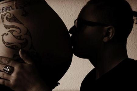 Gustav küsst den Babybauch seiner Frau