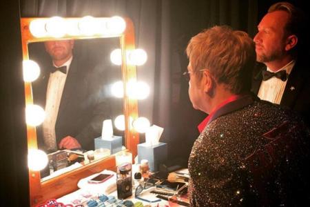 Elton John (l.) muss sich für eine Brille entscheiden - Ehemann David Furnish steht ihm beratend zur Seite