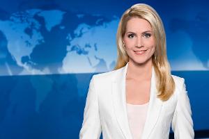 "Tagesschau"-Sprecherin Judith Rakers hebt sich mit ihrem weißen Blazer deutlich vom blauen Hintergrund ab