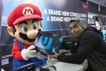 Ein Mario-Maskottchen händigt einem Kunden die derzeit noch aktuelle Nintendo-Heimkonsole Wii U aus