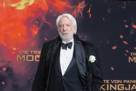 Donald Sutherland alias President Snow warf sich in einen schwarzen Smoking - inklusive weißer Rose.