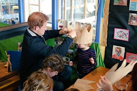 Prinz Harry platziert liebevoll eine Papierkrone auf dem Kopf des Jungen