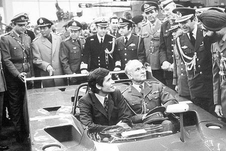 Der Ferrari-Werksfahrer Jacky Ickx im Ferrari-Prototyp - umrahmt von Militär-Attaches ausländischer Nationen.