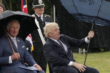 Prinz Charles (li.) kann sich ein Lächeln über Boris Johnsons Schirm-Problem nicht verkneifen.