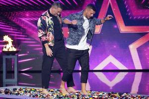 Michael Michalsky und Lukas Podolski (r.) wagen sich barfuß über die Legosteine.