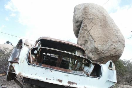 Optische Täuschung: Als wäre der Felsbrocken auf das verrostete Autogerippe gefallen.