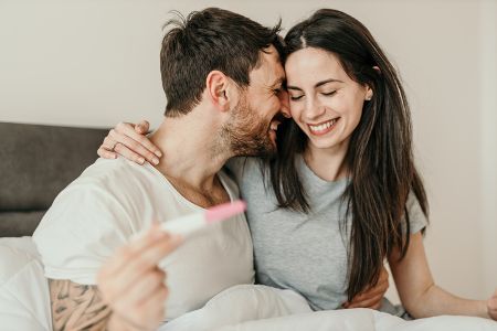 Pärchen freut sich mit Schwangerschaftstest in der Hand