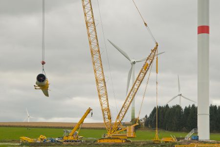 Ein Kran baut eine Windenergieanlage auf.