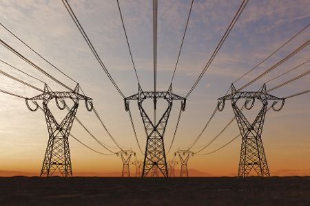 Drei Strommasten mit Stromleitungen vor Sonnenuntergang.