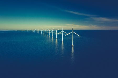 Offshore-Windkraftanlagen in einer Reihe im Meer bei Sonnenschein.