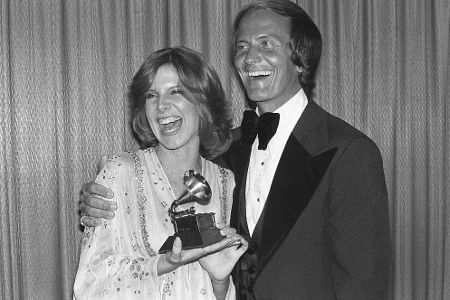 Junge Frau mit Preis im Arm steht neben altem Mann