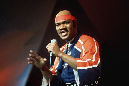 Schwarzer Mann mit Stirnband und Mikrofon beim Singen