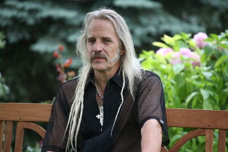 Mann mit langen Haaren und Zöpfchen schaut in die Kamera