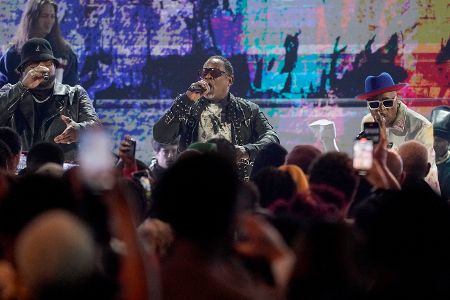 Drei schwarze Männer mittleren Alters mit Sonnenbrillen performen auf einer Bühne