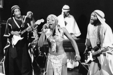 Vier schwarze Musiker und eine schwarze Sängerin musizieren auf einer Bühne