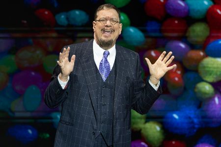 Mann auf Bühne hebt erklärend beide Hände