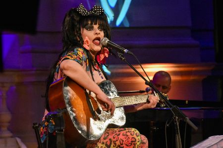 Bunt geschminkte Frau mit Gitarre auf einer Bühne