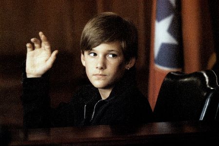 Kleiner Junge hebt die Hand zum Schwur im Gerichtsstand