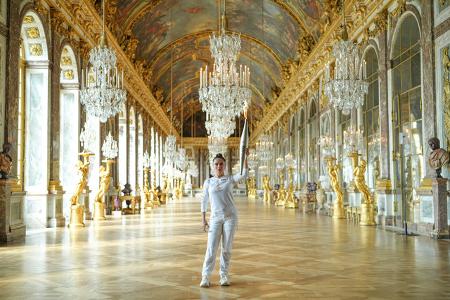 Salma trug die Fackel durch die goldene Pacht von Versailles, darunter den legendären Spiegelsaal.