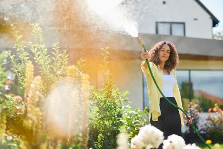 frau sprengt garten in der sonne