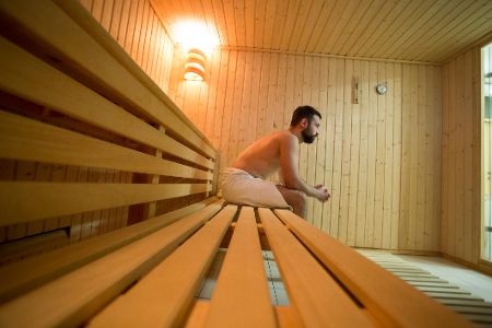 Mann sitzt in sauna und blickt nach vorn