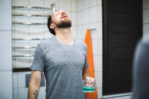 Mann hält Kopf zum Gurgeln in den Nacken