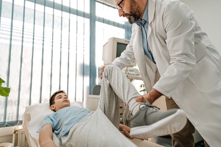 Arzt untersucht Bein von Patienten auf Liege