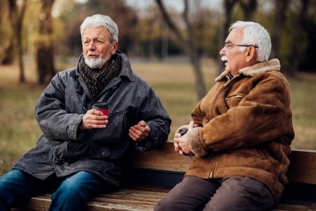 Zwei ältere Männer unterhalten sich auf einer Parkbank